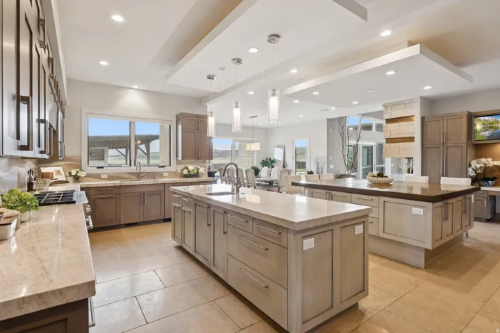 Spacious kitchen featuring two large islands with stone countertops, integrated sink, and ample cabinetry