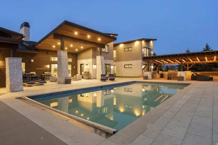 Expansive outdoor living area featuring a large swimming pool, extensive paved patio, and a covered patio with a wood-plank ceiling