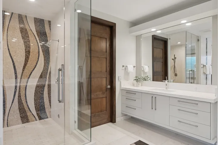 Glass-enclosed shower with a mosaic tile accent wall