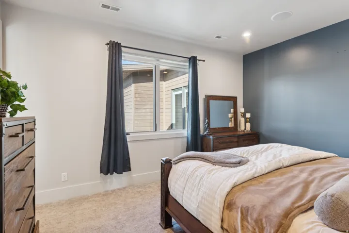 Interior room featuring light-colored carpet flooring, a window with white trim, and a deep blue accent wall