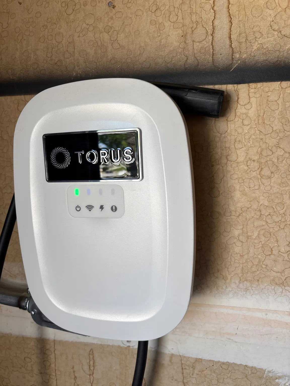 Wall-mounted EV charger featuring a white casing and digital display