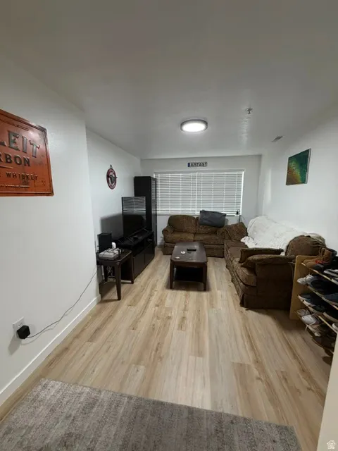 Spacious room featuring wood-finish flooring, a contemporary flush-mount ceiling light, and a window with blinds