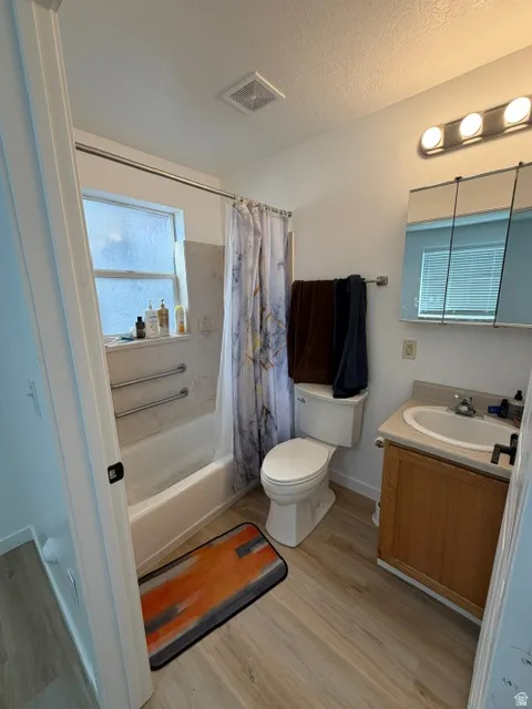 Bathroom featuring a white bathtub, wood-finish flooring, and a single vanity with a laminate countertop