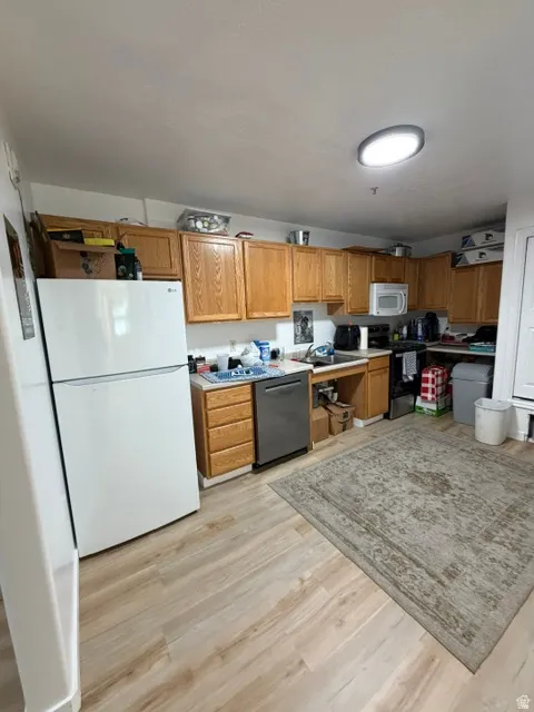 Kitchen featuring wood-finish flooring, recessed lighting, wood cabinetry, and a white refrigerator