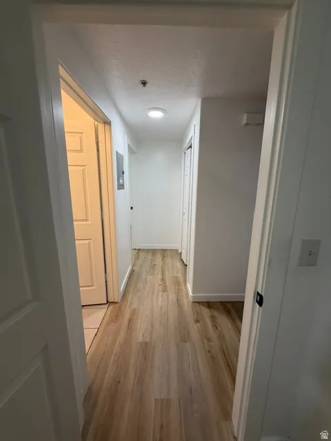 Hallway with wood-finish flooring, white walls, recessed lighting, and white trim