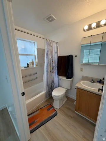 Bathroom featuring a white bathtub, wood-finish flooring, and a single vanity with a laminate countertop