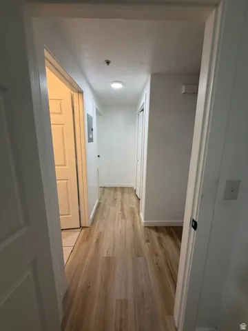 Hallway with wood-finish flooring, white walls, recessed lighting, and white trim