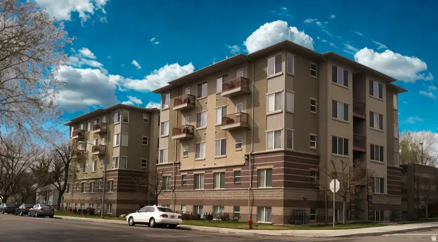 Multi-story residential buildings featuring balconies with metal railings, a stucco facade, and brick accent banding