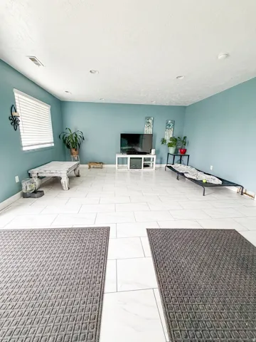 Spacious room featuring white rectangular floor tiles, soft blue walls, and recessed ceiling lighting