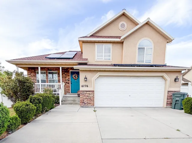Stucco exterior residence featuring a two-car garage, concrete driveway, and an teal front door