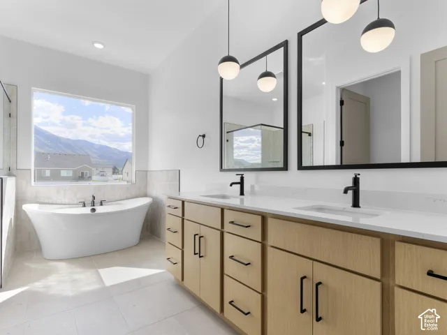 Freestanding soaking tub with a large window, dual vanity with wood-finish cabinetry, built-in sinks, and contemporary black-framed mirrors
