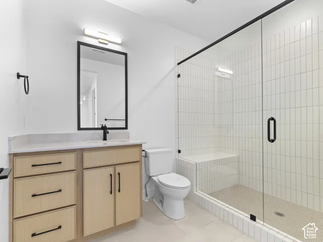 Wood-finish vanity with a light-colored countertop, rectangular mirror, glass-enclosed shower with subway tile, and a built-in shower bench