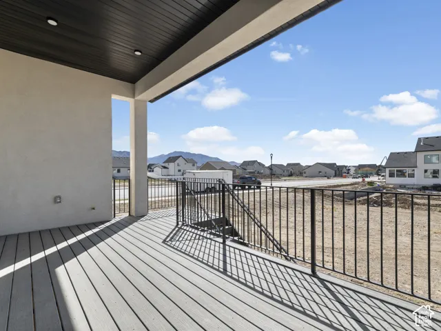 Covered outdoor deck with composite decking, black metal railings, and a horizontal plank ceiling