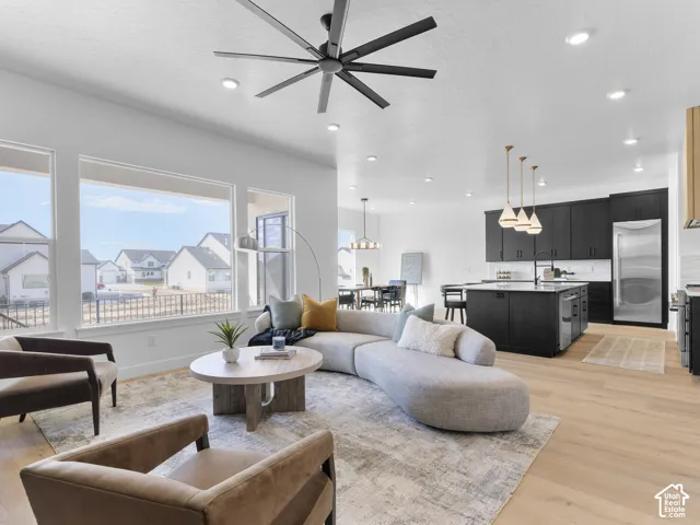 Expansive windows, light wood-finish flooring, recessed lighting, a contemporary ceiling fan, and dark cabinetry