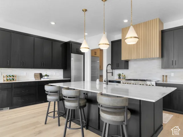 Spacious kitchen featuring dark wood-finish cabinetry, a large center island with a white countertop, and light wood-finish flooring