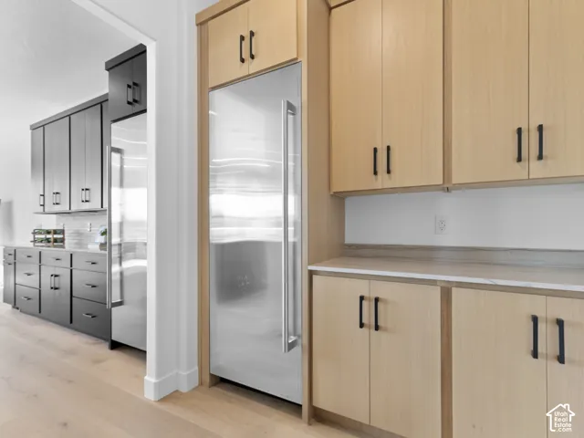 Stainless steel refrigerator integrated with light wood-finish cabinetry