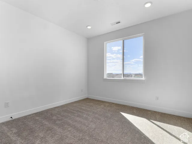Recessed ceiling lighting, neutral tone carpet, white window trim, and white walls