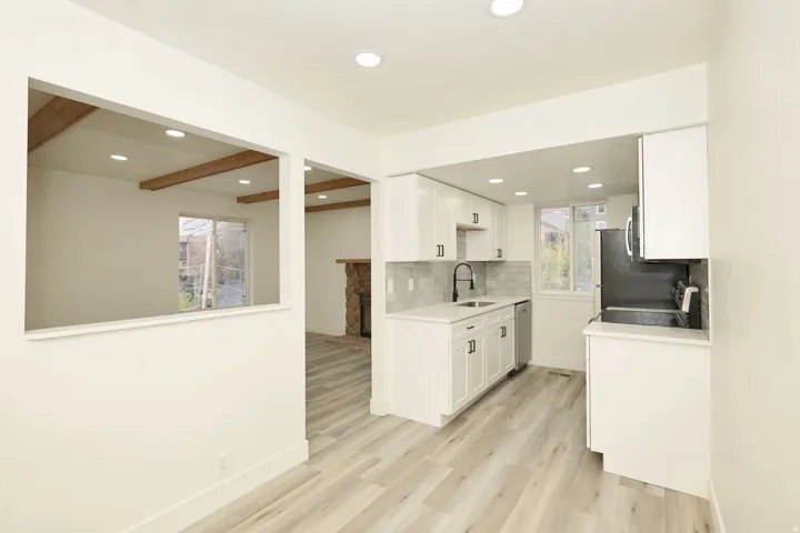 Contemporary kitchen featuring light wood-finish flooring, white cabinetry, a subway tile backsplash, and recessed lighting