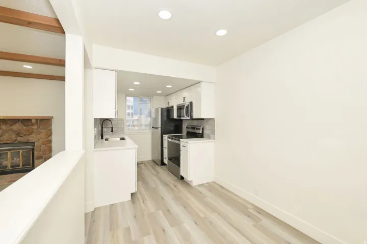 Modern kitchen featuring white cabinetry, light-toned wood-finish flooring, and recessed lighting
