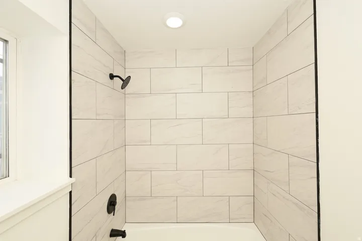 Bathtub with large format rectangular wall tiles and matte black fixtures