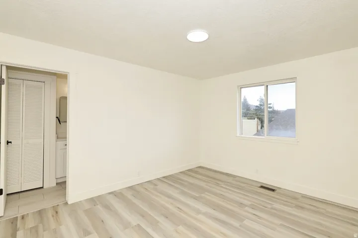 Bright room featuring light wood-finish flooring, a single window, and a flush-mount ceiling light fixture
