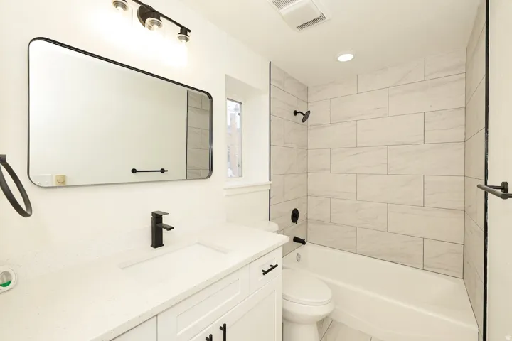 Bathroom featuring a white vanity with integrated sink, a dark bronze faucet, and a rectangular mirror