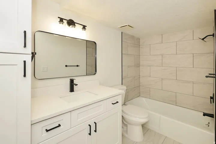 Bathroom featuring a white vanity with integrated sink, quartz-finish countertop, and matte black fixtures