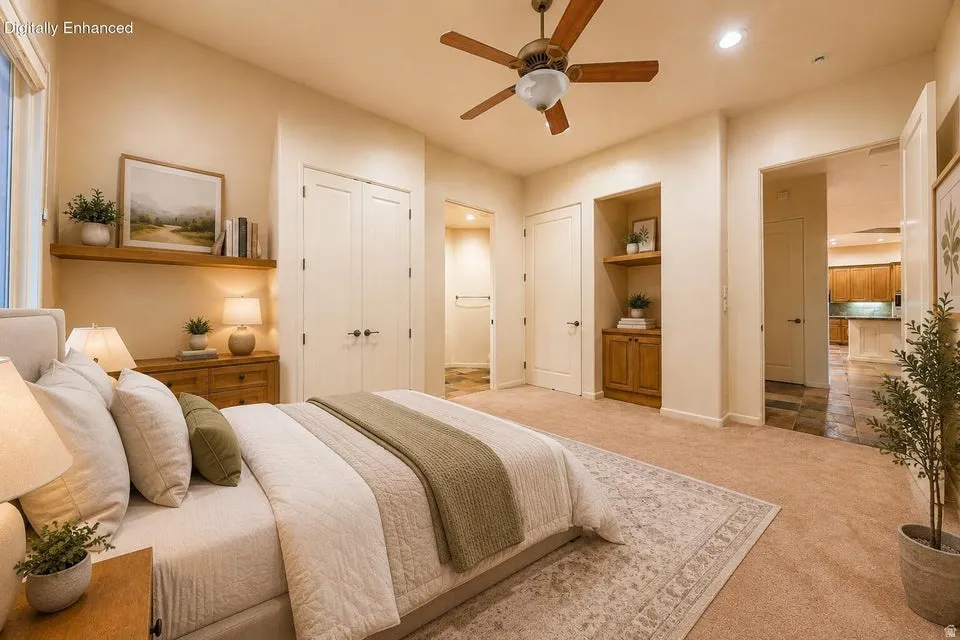 Plush carpet flooring, wood-finish ceiling fan, built-in shelving with wood-finish cabinetry, and double-door closets
