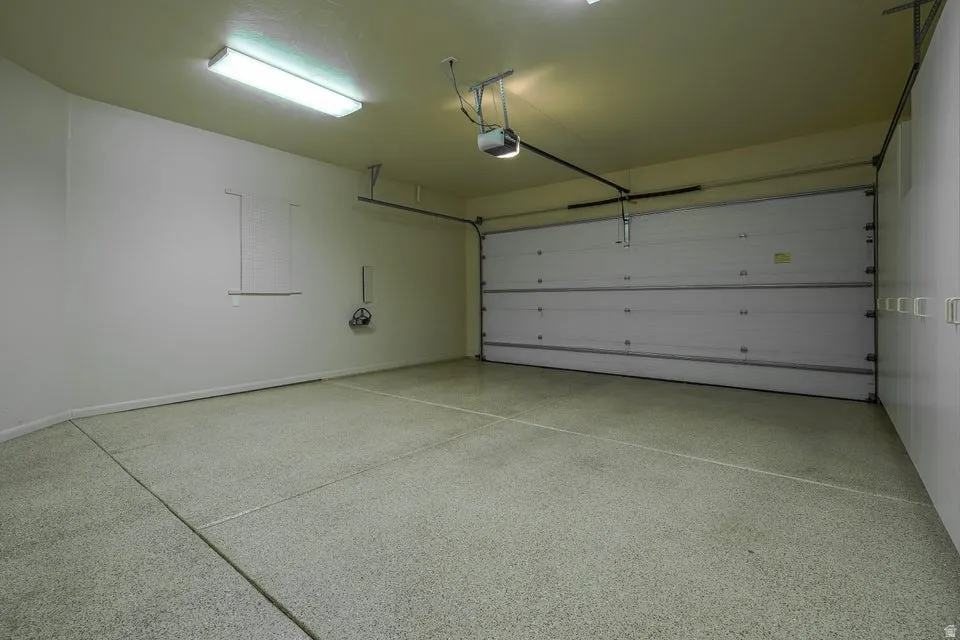 Garage featuring an automatic overhead door, epoxy-coated concrete flooring, and fluorescent lighting