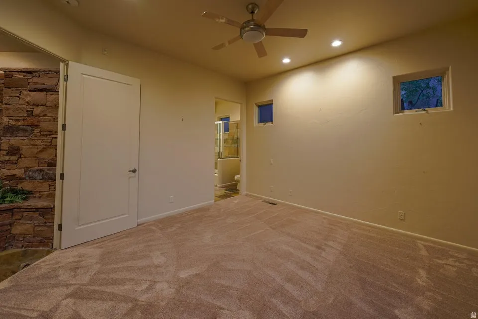 Plush carpeting, recessed lighting, ceiling fan, and stone accent wall
