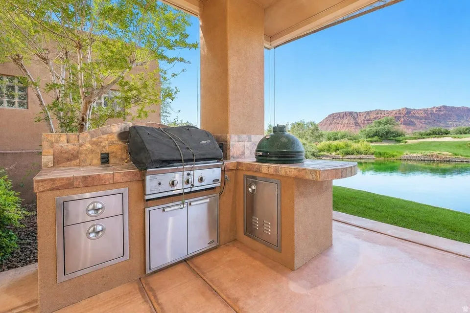 Outdoor kitchen featuring built-in grill, stainless steel appliances, and tiled countertops