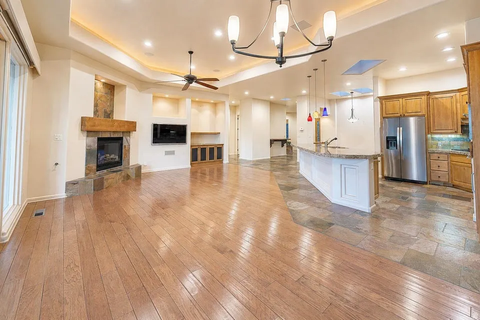 Wood-finish flooring, recessed lighting, and a corner fireplace with a wood mantle