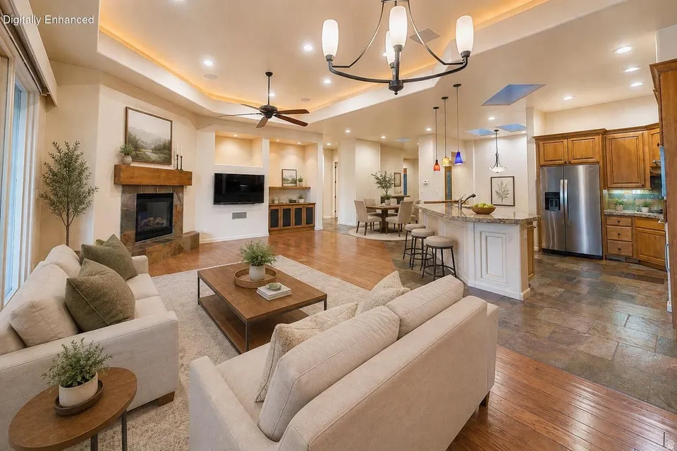 Living area featuring a stone fireplace with a wood mantle, tray ceiling with recessed lighting, and a ceiling fan