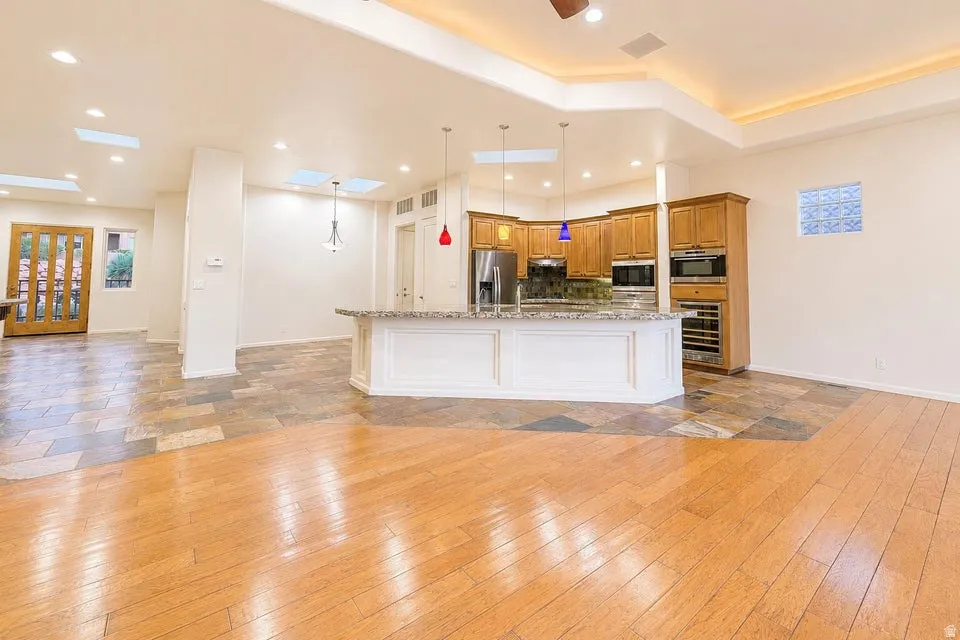 Recessed ceiling lighting, tray ceiling with cove lighting, skylights, wood-finish flooring, and natural stone tile flooring