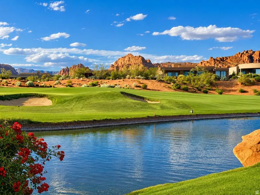 Expansive water feature with adjacent manicured green space, surrounded by natural red rock formations and desert landscaping