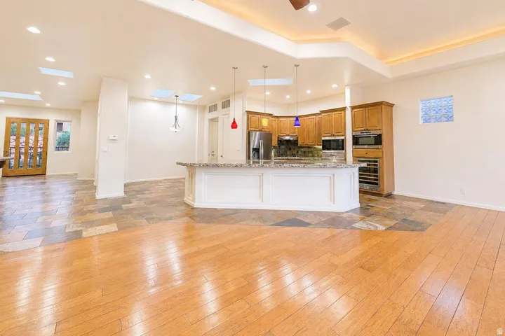 Recessed ceiling lighting, tray ceiling with cove lighting, skylights, wood-finish flooring, and natural stone tile flooring