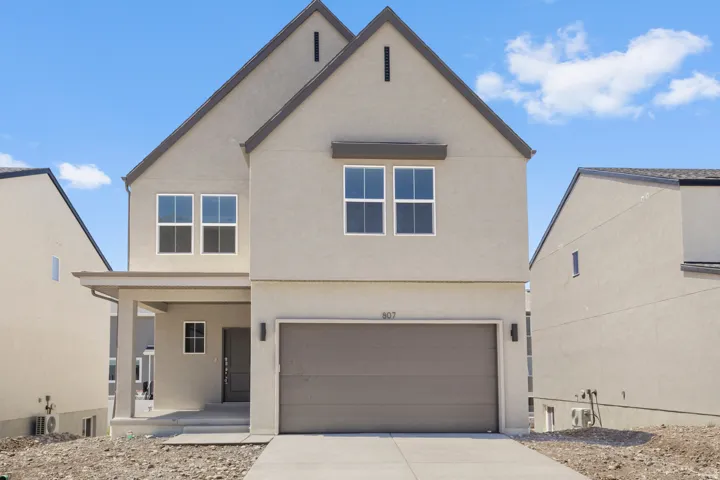 Contemporary stucco exterior featuring a two-story design, covered porch, attached garage, and prominent gabled rooflines