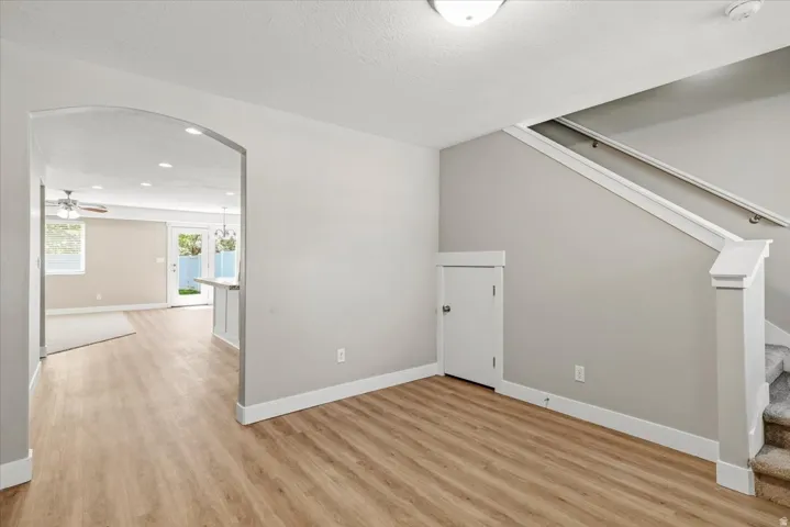 Light wood-finish flooring extending through an arched entryway. New flooring throughout entry and front room