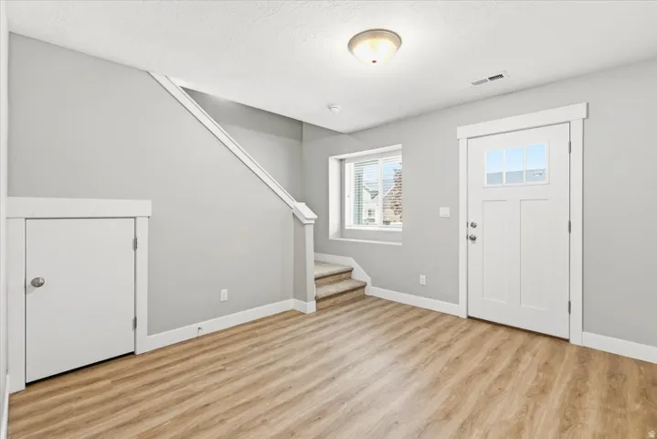 Entryway featuring a white paneled door with glass inserts, wood-finish flooring, a carpeted staircase, and a built-in storage closet