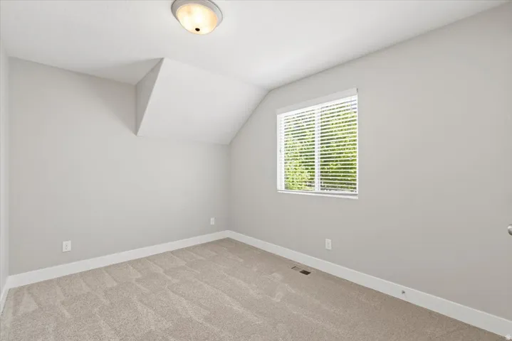 Carpeted room featuring a single window with blinds, light gray wall paint, and white trim