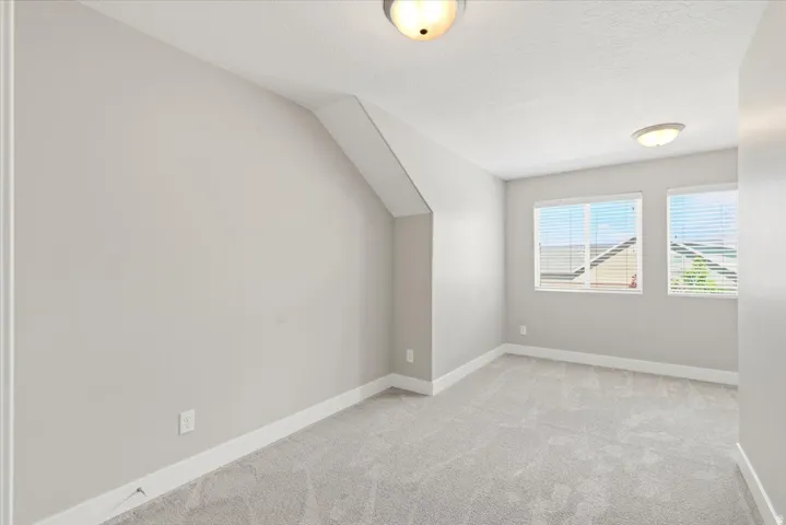 Carpeted interior room with white baseboards, two windows, and two flush-mount ceiling lights