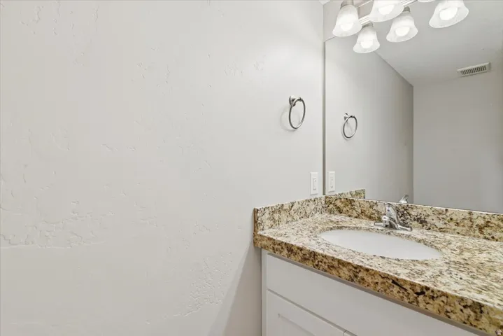 1.2 bath on main. Bathroom vanity featuring a speckled countertop, undermount sink, and chrome faucet