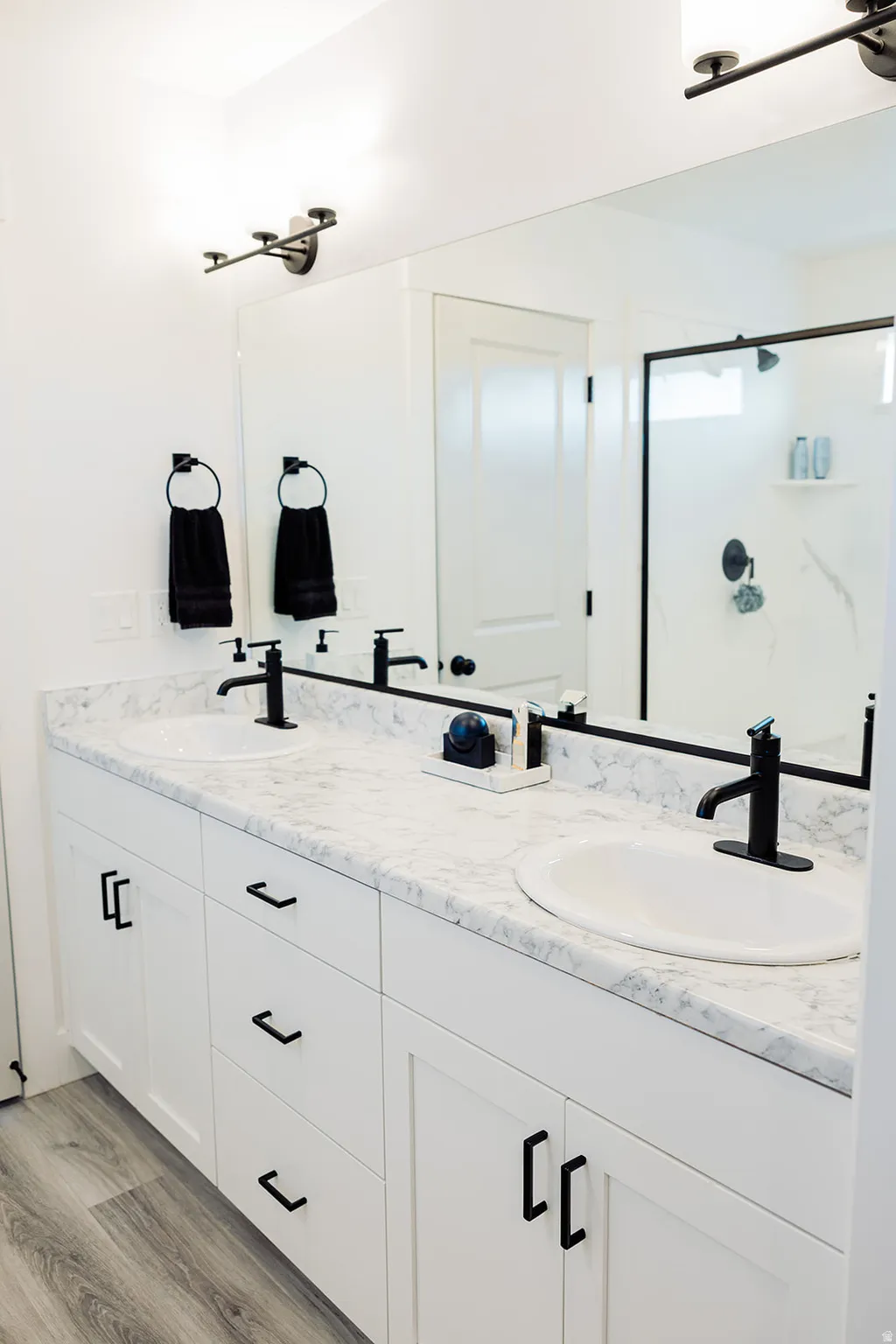 Dual vanity with white cabinetry and matte black hardware, featuring a light-colored countertop with integrated sinks and matte black faucets