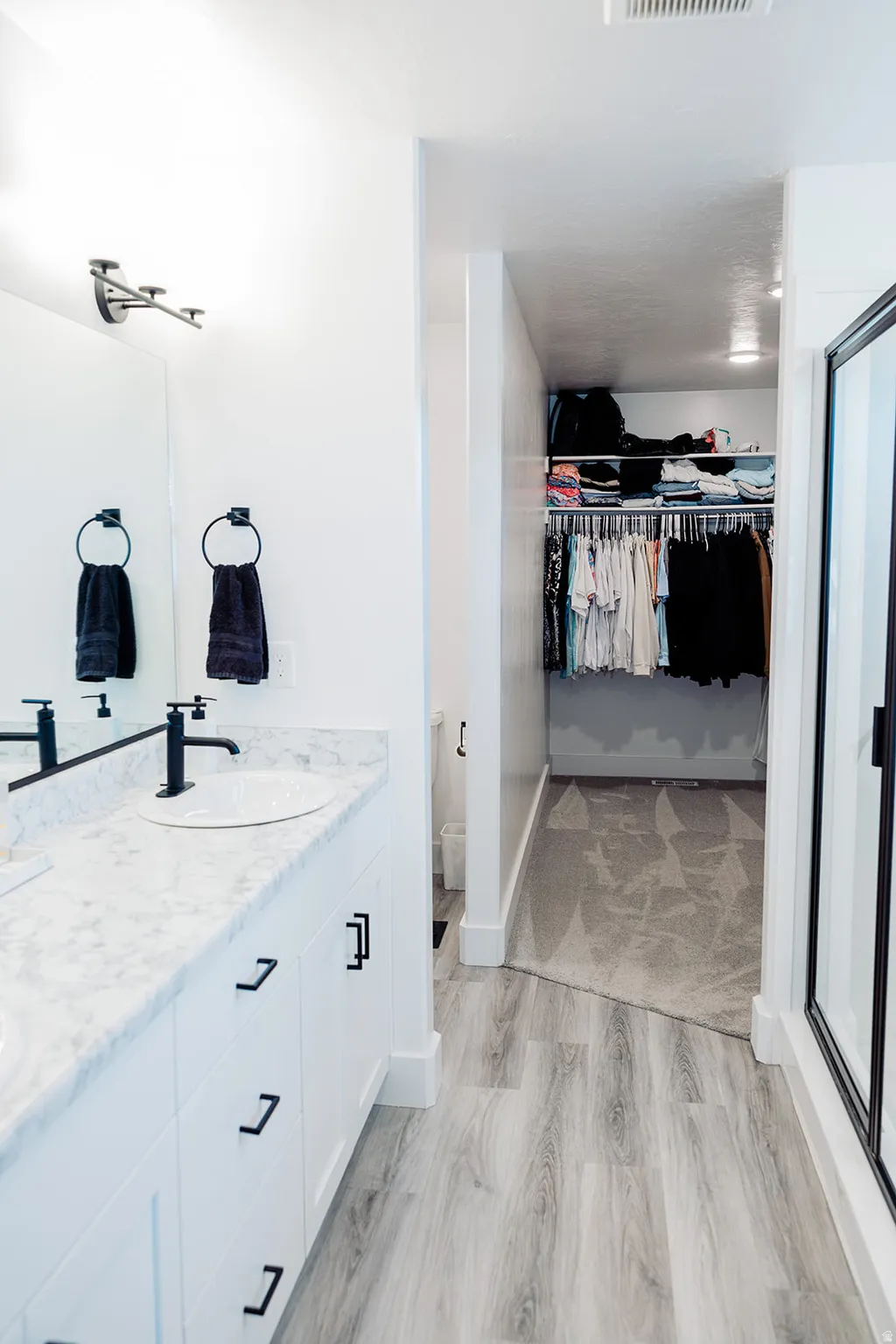 Bathroom vanity with dual undermount sinks, stone-finish countertop, and black hardware