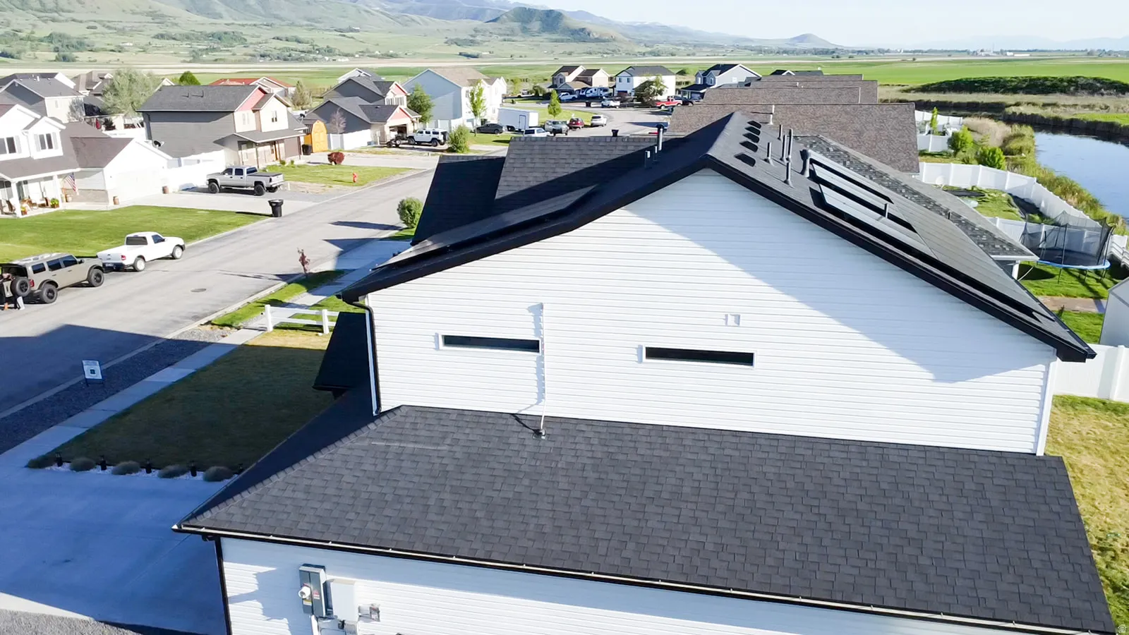 Contemporary siding exterior with a dark shingle roof and integrated solar panels facing East and West.