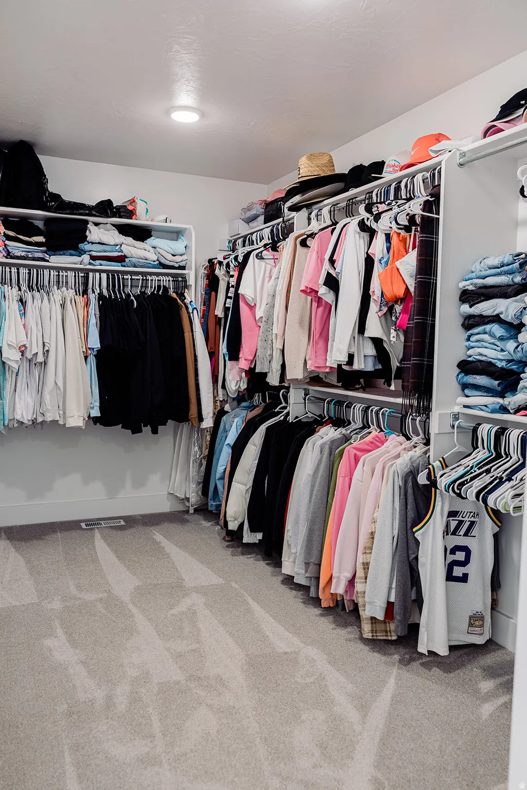 Spacious walk-in closet featuring wall-mounted shelving and ample hanging rods