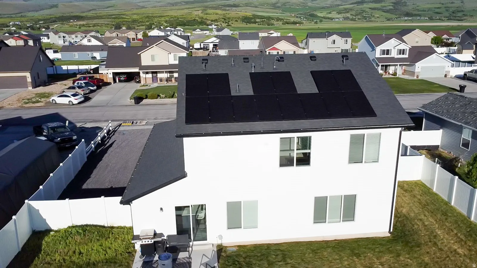 Contemporary two-story residence with a white exterior and a dark shingle roof featuring solar panels