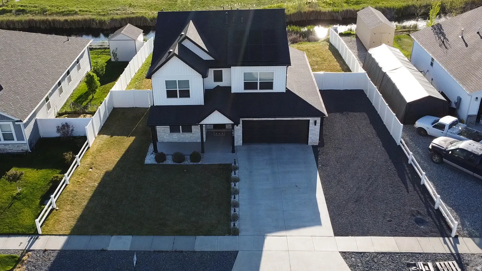 Contemporary two-story residence featuring a dark roof, white siding with dark trim, and a covered front porch with stone accents. East facing. Extra Parking.