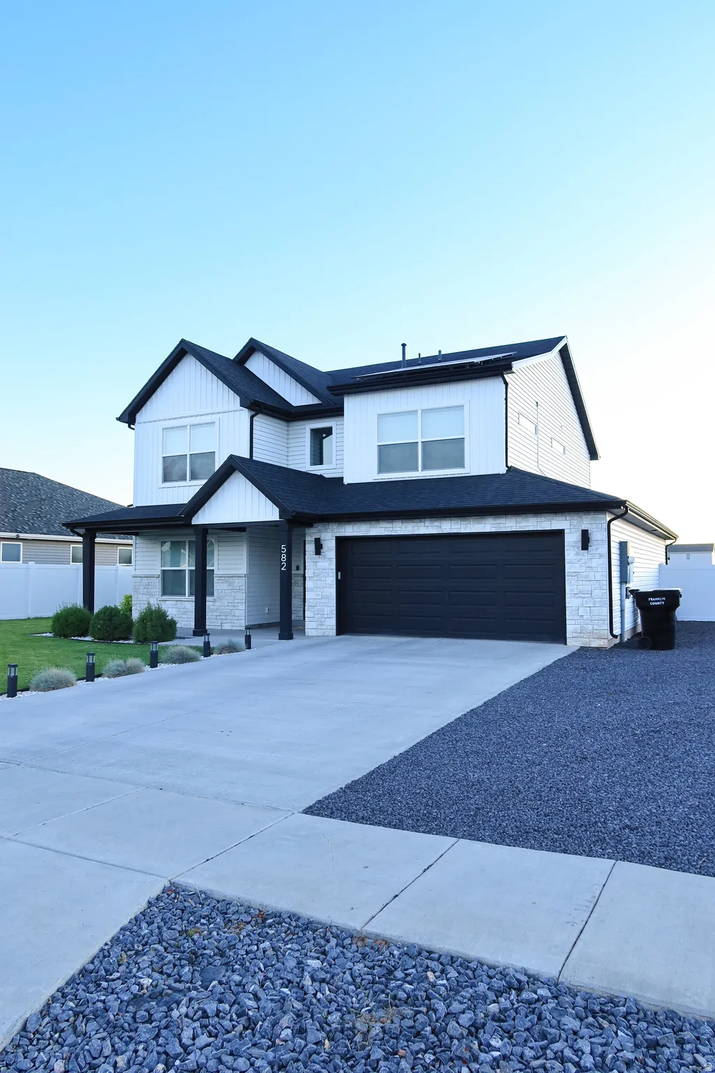 Two-story residence featuring white vertical and horizontal siding with black trim accents