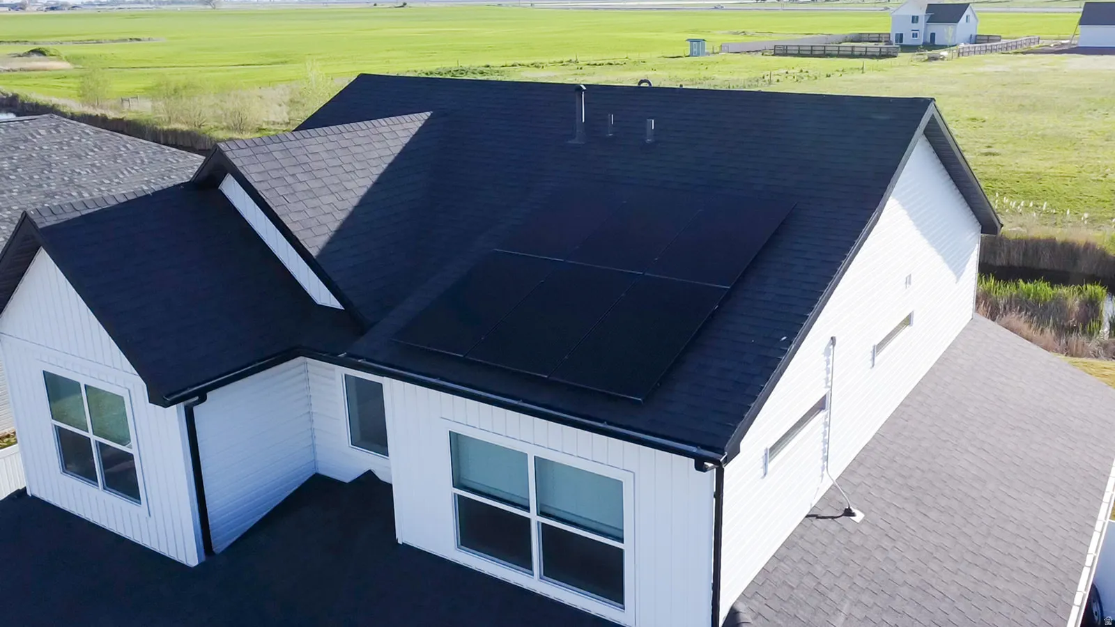 Modern residential architecture featuring dark shingle roofing, white vertical siding, and east facing solar panels.
